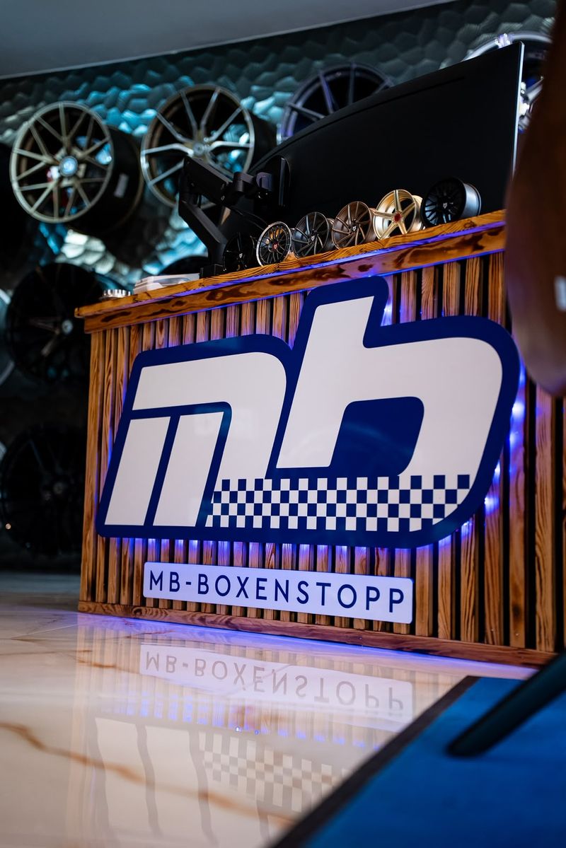 Beleuchtetes MB-Boxenstopp Logo am Holztresen im Showroom